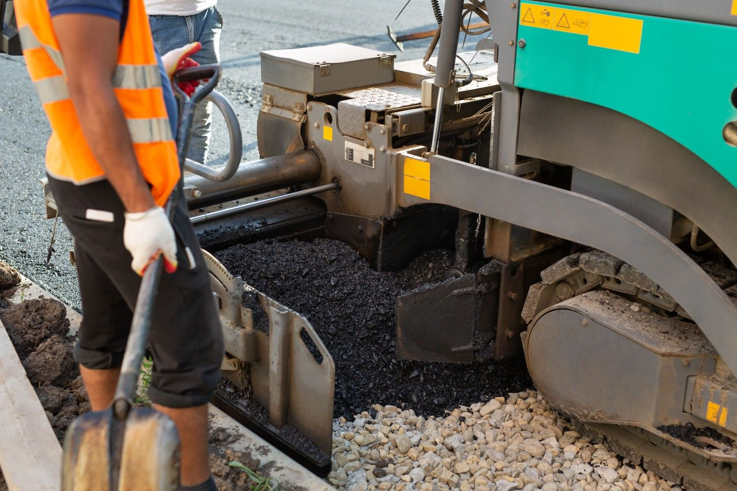 Asphalt spreader paver machine resurfacing a road, demonstrating professional paving services in Woodstock