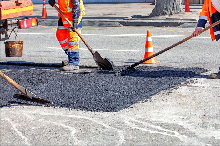 Asphalt patcher filling cracks with hot mix during a professional asphalt repair service.
